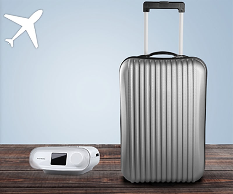 le dreamstation à côté d'une valise et un avion (le Dreamstation est un excellent compagnon de voyage)