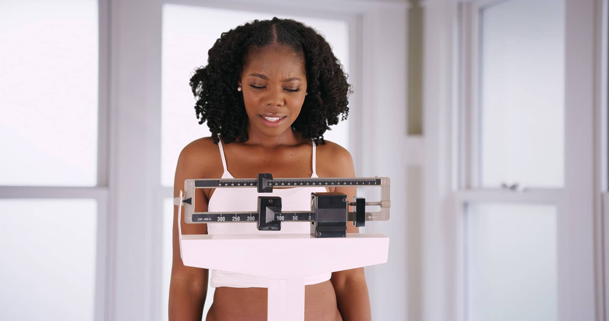 Woman looks at her weight while standing on a scale