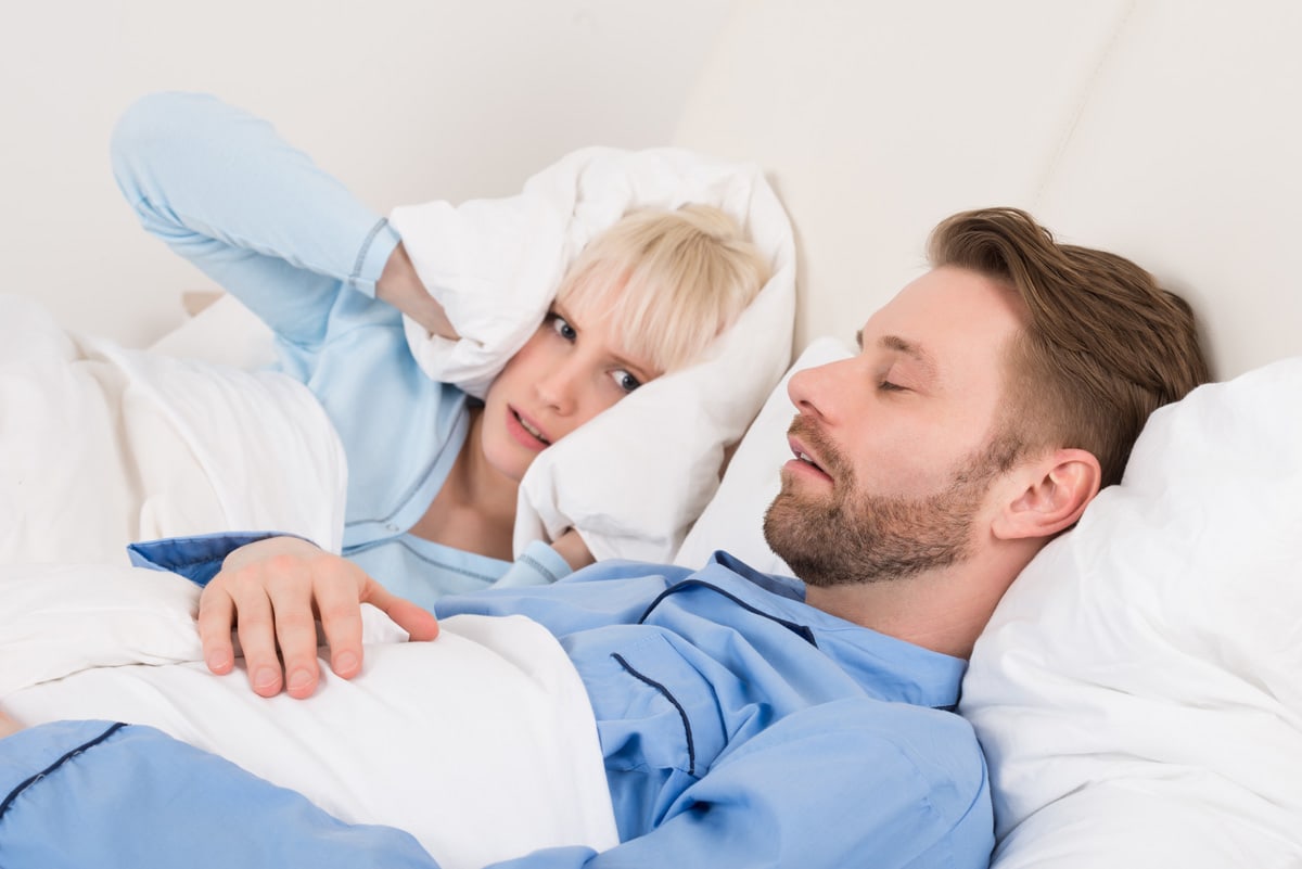 Snoring man in bed with his angry partner