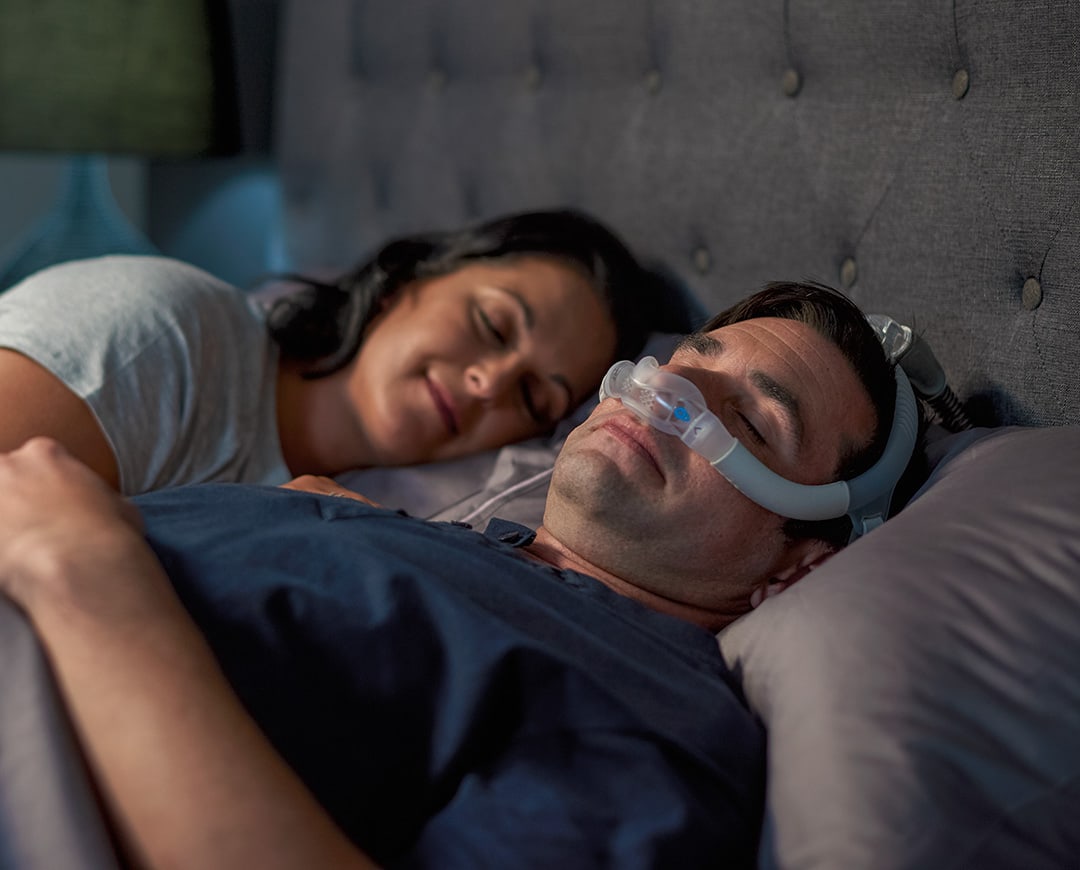 homme qui dort dans son lit avec un masque CPAP