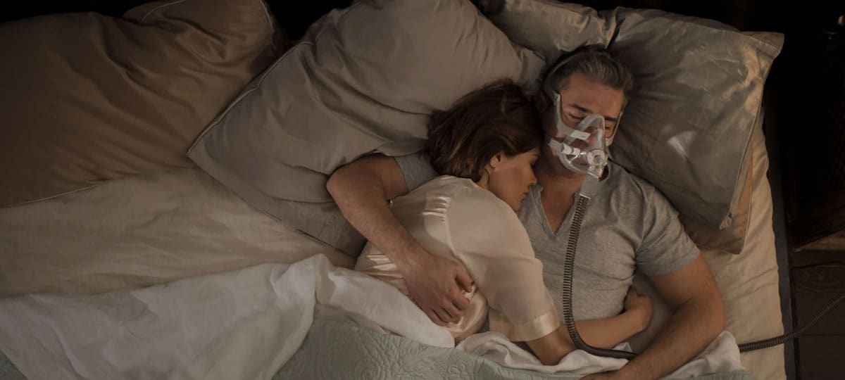 man wearing an AirFit F20 mask in bed