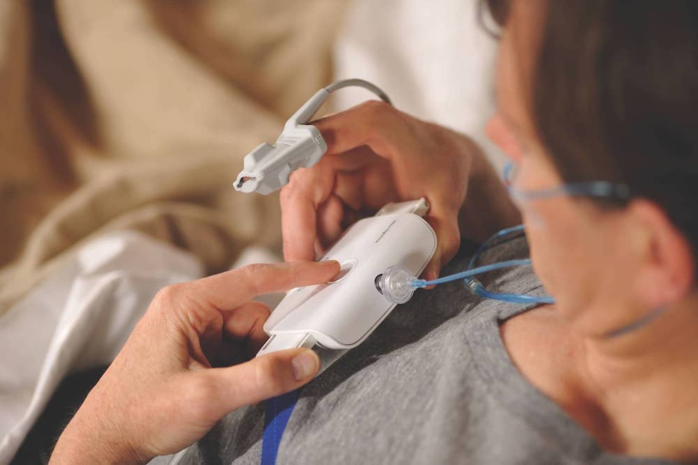 Man in bed adjusting the home sleep test monitor around his chest