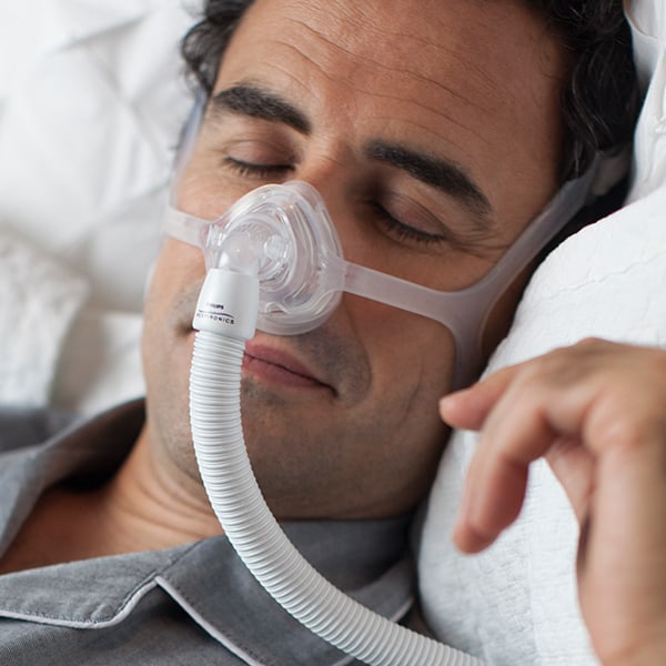 Homme endormi tout en portant un masque nasal Wisp