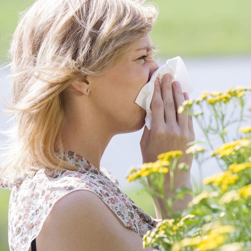 woman next to flowers, blowing her nose
